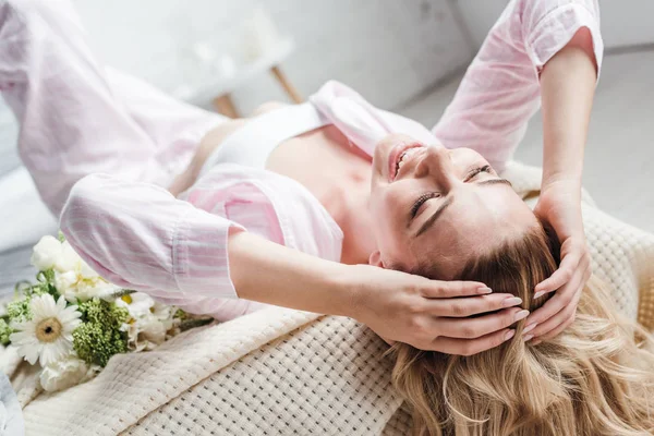 Вибірковий фокус усміхненої молодої жінки, що лежить біля квітів на ліжку — стокове фото