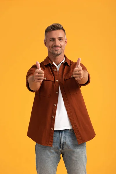 Homem alegre mostrando polegares isolados em laranja — Fotografia de Stock