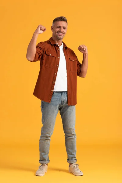 Cheerful man standing with clenched fists on orange — Stock Photo