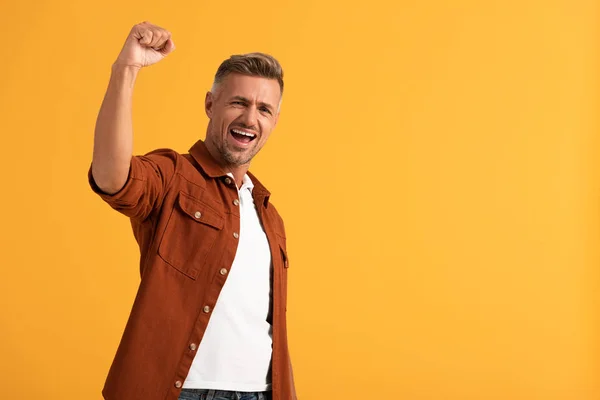 Hombre excitado con el puño cerrado celebrando aislado en naranja - foto de stock