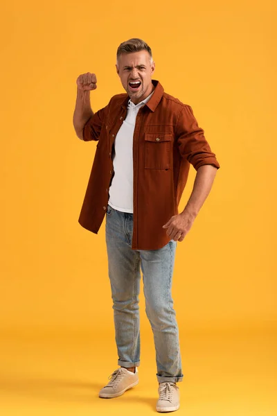 Angry man with clenched fist screaming on orange — Stock Photo