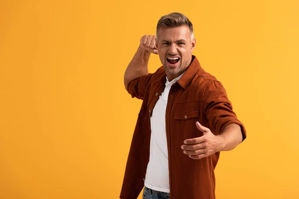 Angry man with clenched fist screaming isolated on orange — Stock Photo