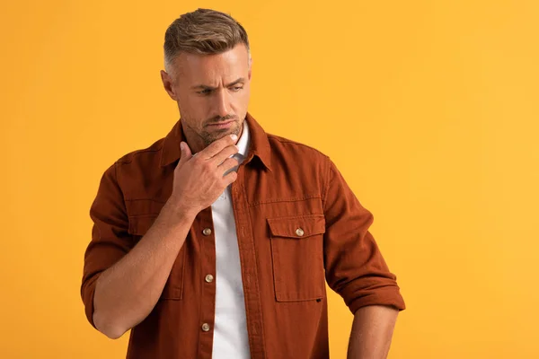 Handsome man touching face while thinking isolated on orange — Stock Photo