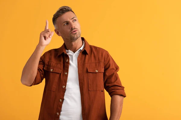 Hombre guapo gesto mientras tiene idea aislado en naranja - foto de stock