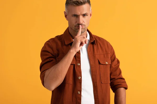 Hombre guapo mostrando signo de silencio aislado en naranja - foto de stock