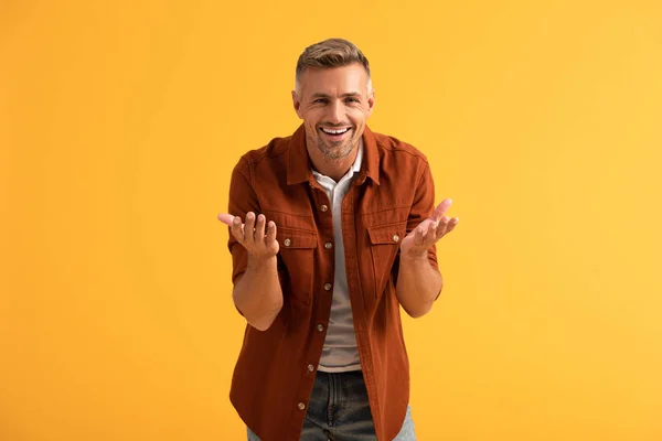 Glücklicher Mann blickt in die Kamera und gestikuliert isoliert auf orange — Stockfoto