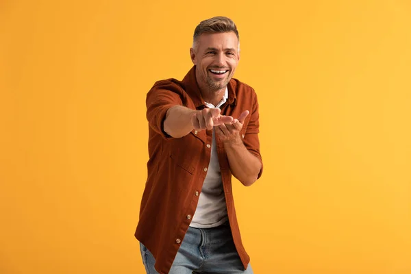 Selective focus of happy man looking at camera and pointing with finger isolated on orange — Stock Photo