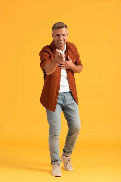 Enfoque selectivo del hombre feliz mirando a la cámara y señalando con el dedo en naranja - foto de stock