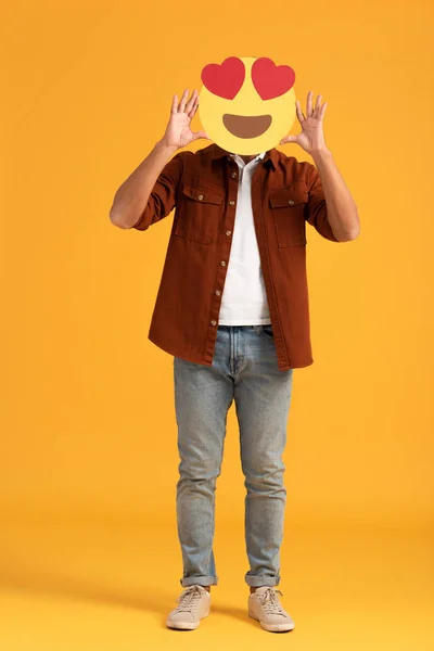 KYIV, UKRAINE - SEPTEMBER 24, 2019: man covering face with heart eyes cartoon emoticon on orange — Stock Photo