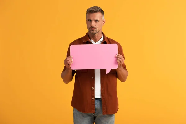 Hombre guapo sosteniendo burbuja de habla rosa aislado en naranja - foto de stock