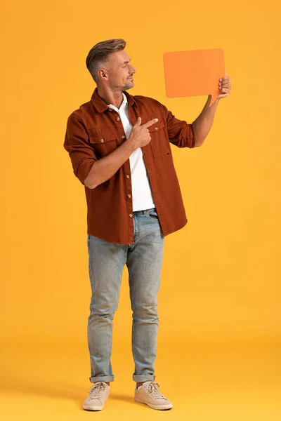 Hombre feliz señalando con el dedo a la burbuja del habla en naranja - foto de stock