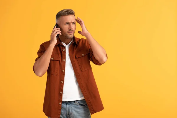 Homem emocional gesticulando enquanto fala no smartphone isolado em laranja — Fotografia de Stock