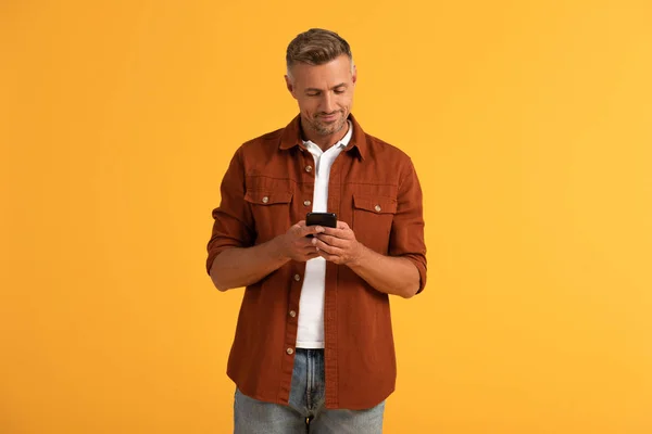 Homme heureux en utilisant smartphone isolé sur orange — Photo de stock