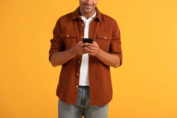 Vista recortada de hombre feliz usando teléfono inteligente aislado en naranja - foto de stock