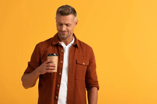 Uomo allegro guardando tazza di carta isolato su arancione — Foto stock