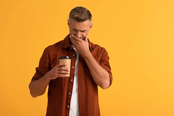 Triste homme couvrant visage tout en regardant tasse en papier isolé sur orange — Photo de stock