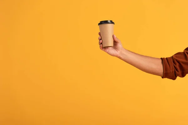 Cropped view of man holding paper cup isolated on orange — Stock Photo