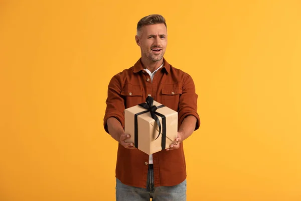 Emotional man holding present isolated on orange — Stock Photo