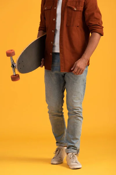 Vista ritagliata di uomo che tiene penny board su arancione — Foto stock