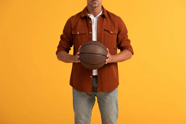 Vista recortada del hombre sosteniendo baloncesto aislado en naranja - foto de stock