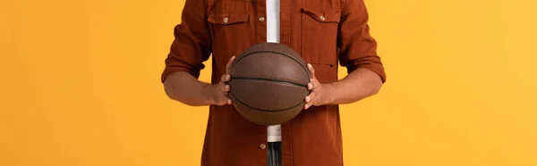 Plano panorámico del hombre sosteniendo baloncesto aislado en naranja - foto de stock