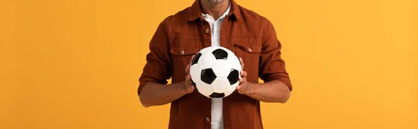 Tiro panorámico del hombre sosteniendo el fútbol aislado en naranja - foto de stock