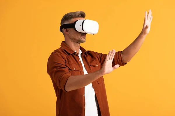 Schöner Mann in Virtual-Reality-Headset gestikuliert isoliert auf orange — Stockfoto