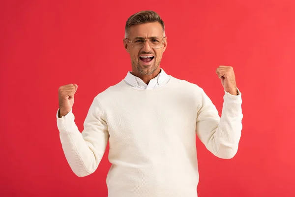 Excité homme dans des lunettes célébrant triomphe isolé sur rouge — Photo de stock