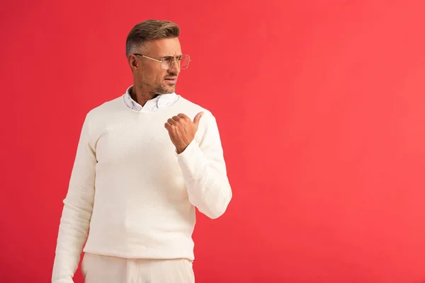 Displeased man in glasses pointing with finger isolated on red — Stock Photo