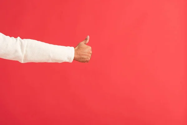 Обрізаний вид людини, що показує великий палець вгору ізольовано на червоному — стокове фото