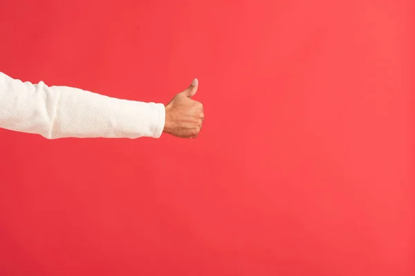 Vista recortada del hombre mostrando el pulgar hacia arriba aislado en rojo - foto de stock