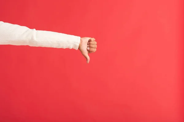 Vista recortada del hombre mostrando el pulgar hacia abajo aislado en rojo - foto de stock