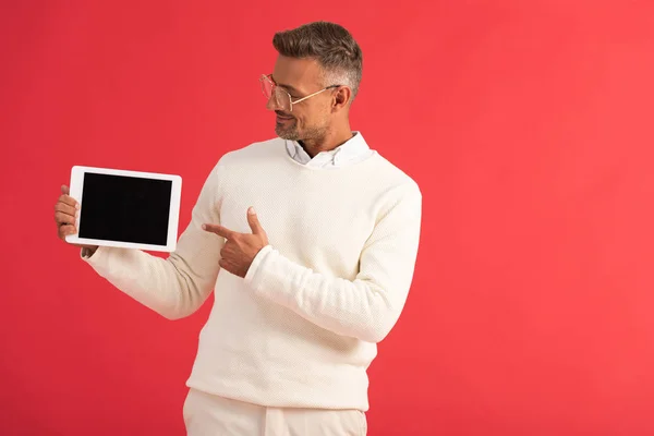 Hombre feliz en gafas apuntando con el dedo a la tableta digital con pantalla en blanco - foto de stock