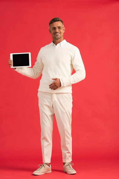 Hombre feliz sosteniendo tableta digital con pantalla en blanco en rojo - foto de stock
