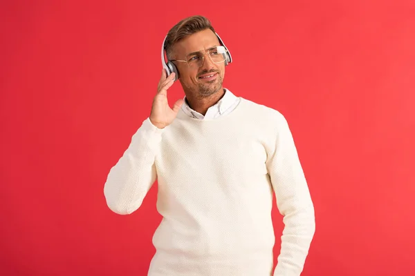 Homme heureux écouter de la musique dans les écouteurs isolés sur rouge — Photo de stock