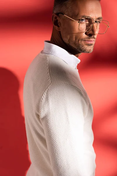 Homme beau et élégant dans des lunettes sur rouge avec des ombres — Photo de stock