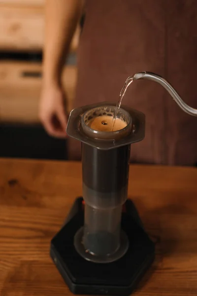 Vista recortada de barista vertiendo agua de la tetera en aeroprensa mientras prepara café - foto de stock