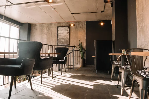 Balkon mit Tischen und Stühlen in modernem Loft-Kaffeehaus im Sonnenlicht — Stockfoto