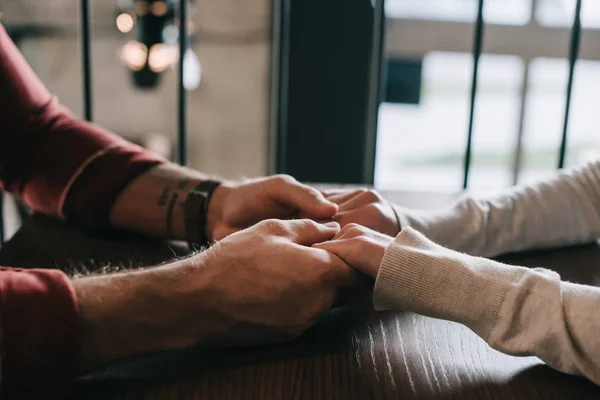 Cropped view of couple holding hands on balcony in coffee shop — Stock Photo