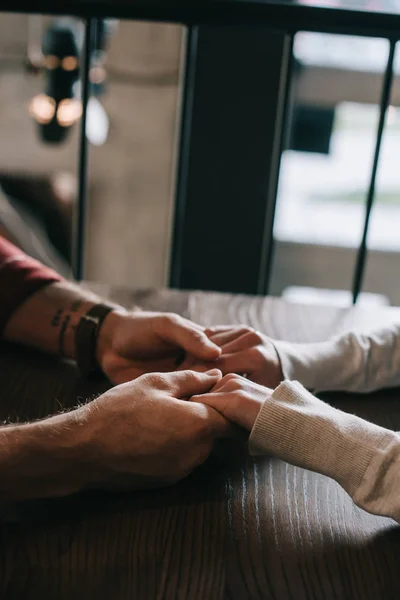 Cropped view of couple holding hands on balcony in coffee shop — Stock Photo