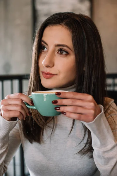 Dreamy young woman with cappuccino on balcony in coffee shop — Stock Photo