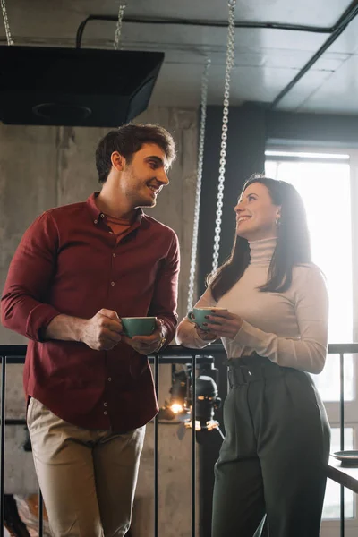 Feliz pareja hablando mientras bebe café en el balcón en la cafetería - foto de stock