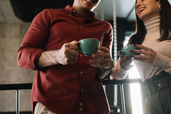 Cropped view of happy couple talking while drinking coffee on balcony in coffee shop — Stock Photo