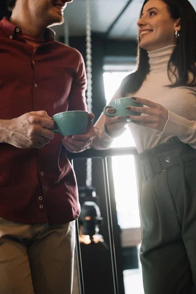 Cropped view of happy couple talking while drinking coffee on balcony in coffee shop — Stock Photo