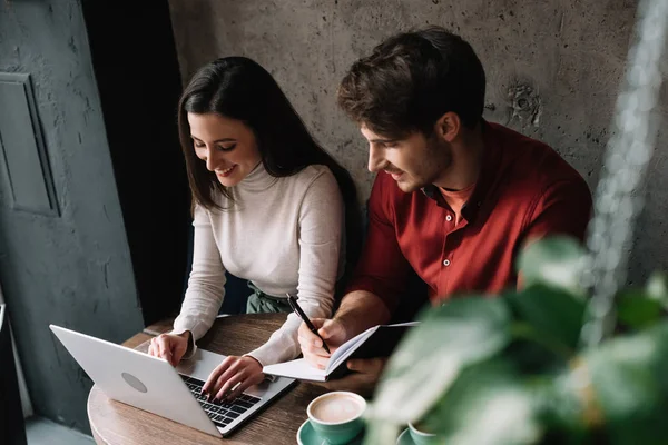 Sorrindo jovem casal trabalhando no laptop no café — Fotografia de Stock