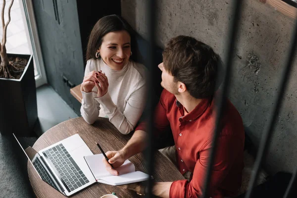 Selektiver Fokus glücklicher junger Paare, die am Laptop arbeiten und sich im Café unterhalten — Stockfoto