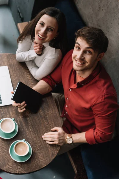 Vista aérea de casal jovem sorridente trabalhando no laptop no café — Fotografia de Stock