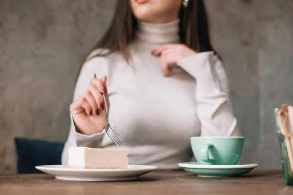 Cropped view of woman eating cheesecake and drinking coffee in cafe — Stock Photo