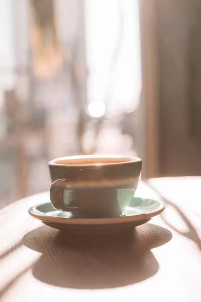 Tasse Kaffee auf Untertasse auf Tisch im Sonnenlicht — Stockfoto