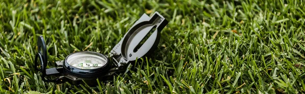 Panoramic shot of black retro compass on green grass — Stock Photo